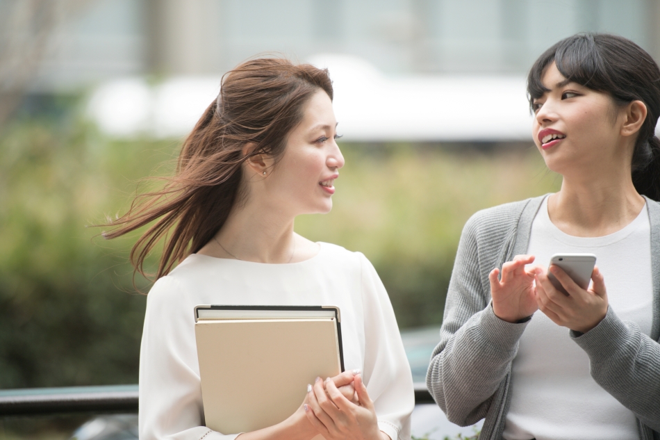 女性二人がスマホと会話をしながら町中を歩いている
